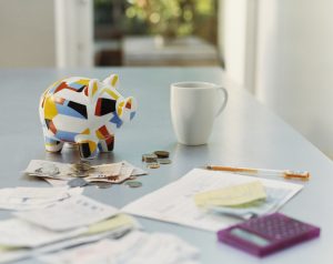 Alcancía de colores, con monedas y billetes alrededor sobre una mesa (Getty Images)