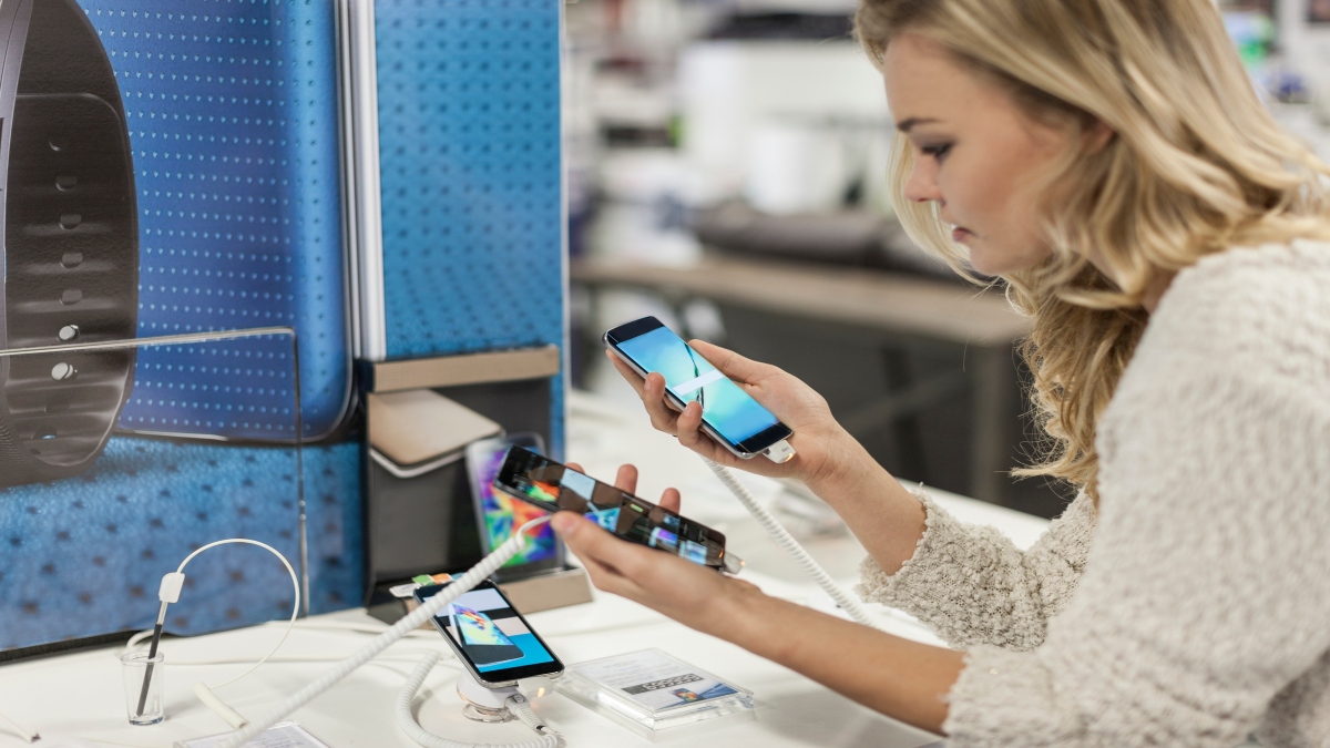Mujer eligiendo celular en tienda de tecnología (Getty Images)