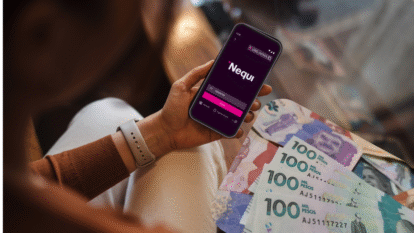 Mano de una mujer sosteniendo un celular con la app de Nequi en pantalla y billetes | Getty -Nequi